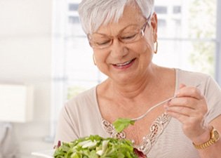 Woman with dentures eating a salad 